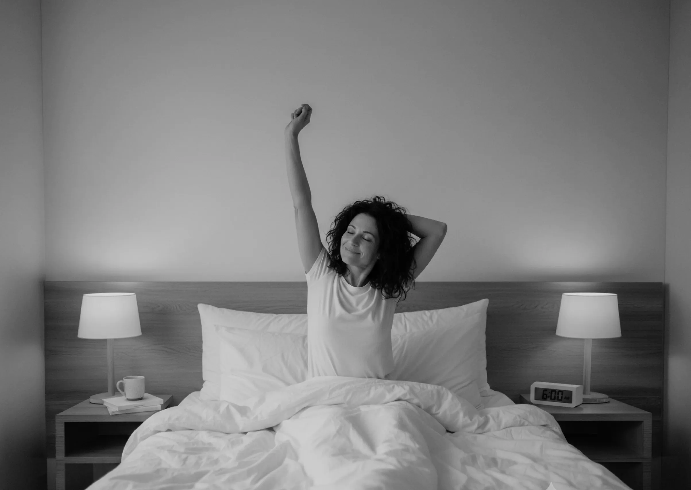 Woman sitting up in bed stretching with one arm raised, flanked by two bedside tables with lamps and clock showing 6:00 AM.