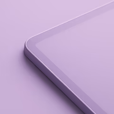 Close-up of a corner of a tablet with a smooth glass screen and rounded edges on a purple surface.