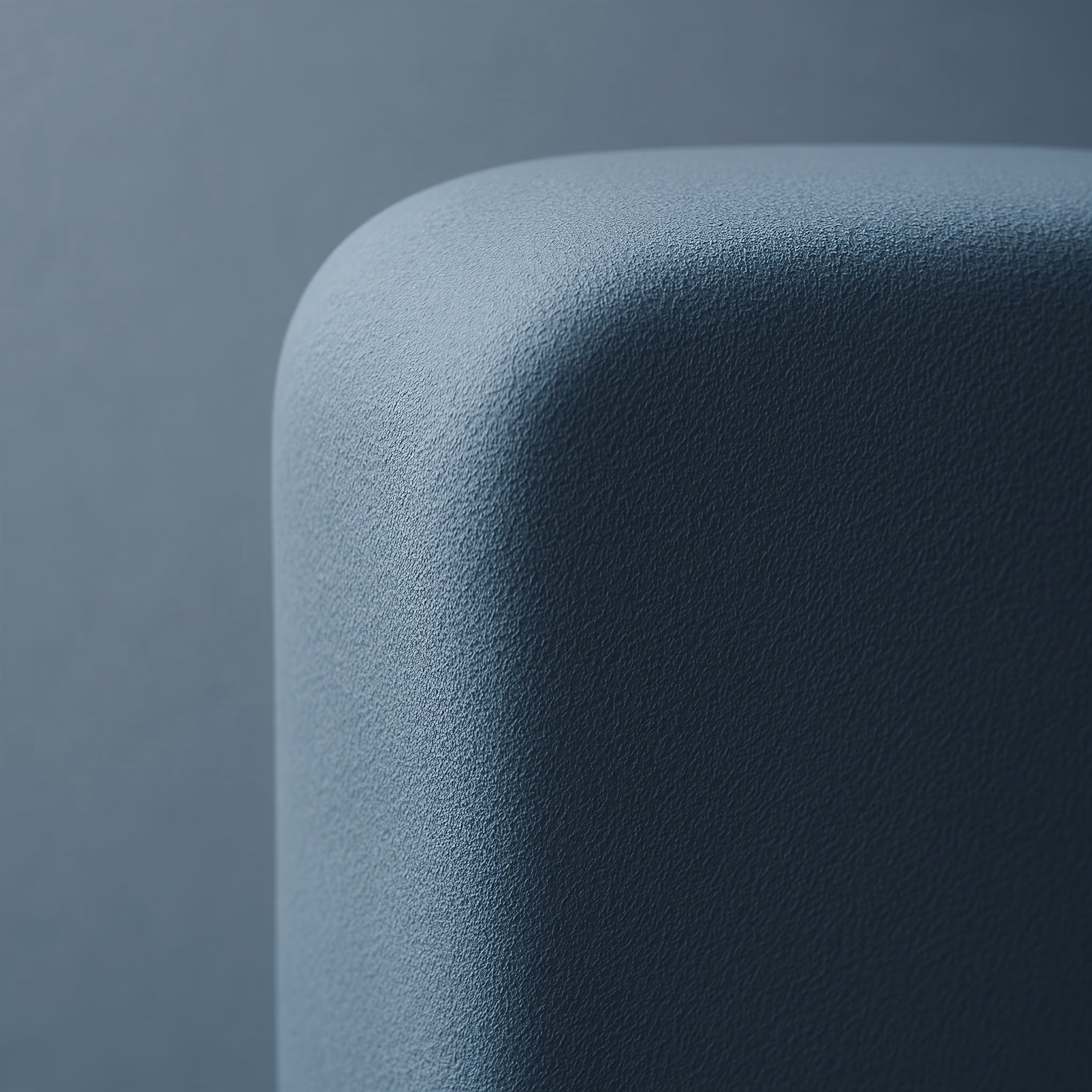 Close-up view of a rounded corner of a textured, dark gray-blue rectangular object against a matching background.