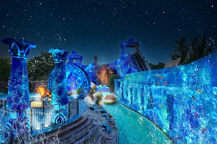 Night-time water ride at Gardaland illuminated with blue lighting and underwater-themed scenery.