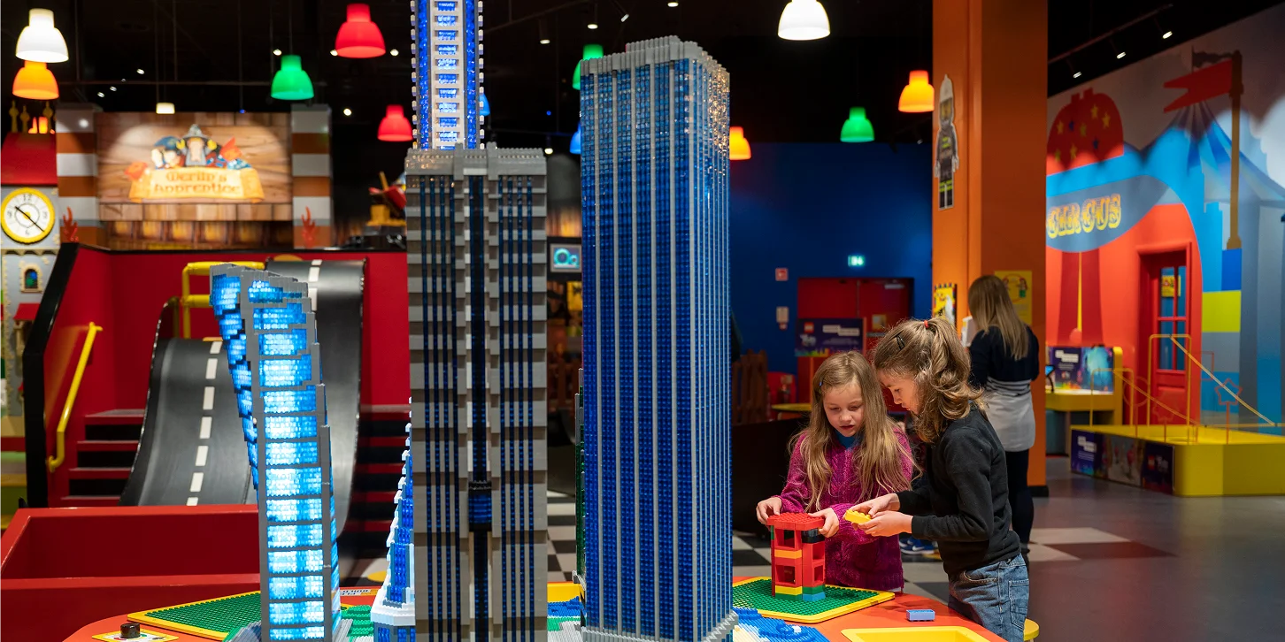 Children playing with LEGO bricks inside a LEGOLAND Discovery Centre, building models in an indoor play area.