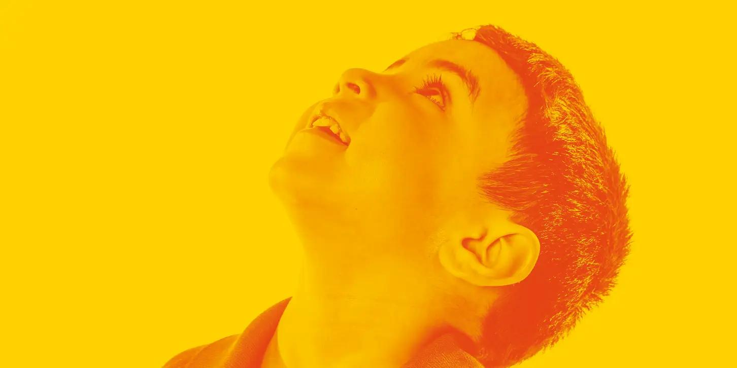Close-up of a young boy looking upwards with a yellow and orange color overlay.