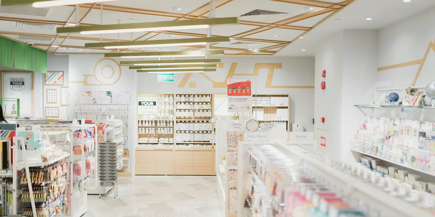 Bright, modern stationery store interior with shelves displaying greeting cards, sticky notes, and various art supplies.