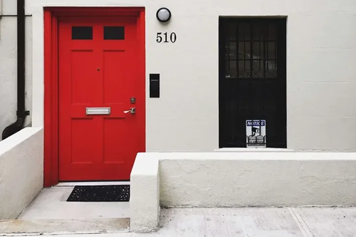 White house facade with a vibrant red front door, black security door, and house number 510.