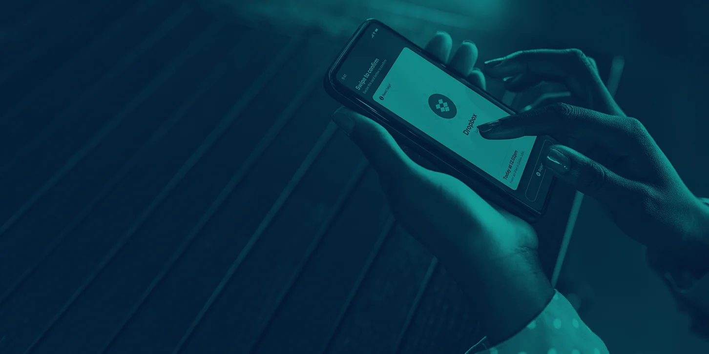 Person holding a smartphone displaying a Dropbox confirmation screen with a swipe to confirm action.