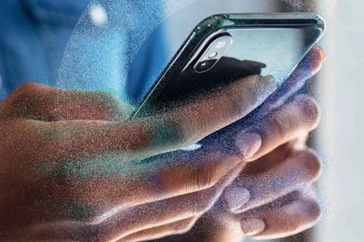 Close-up of hands holding a smartphone with artistic particle effect overlay.