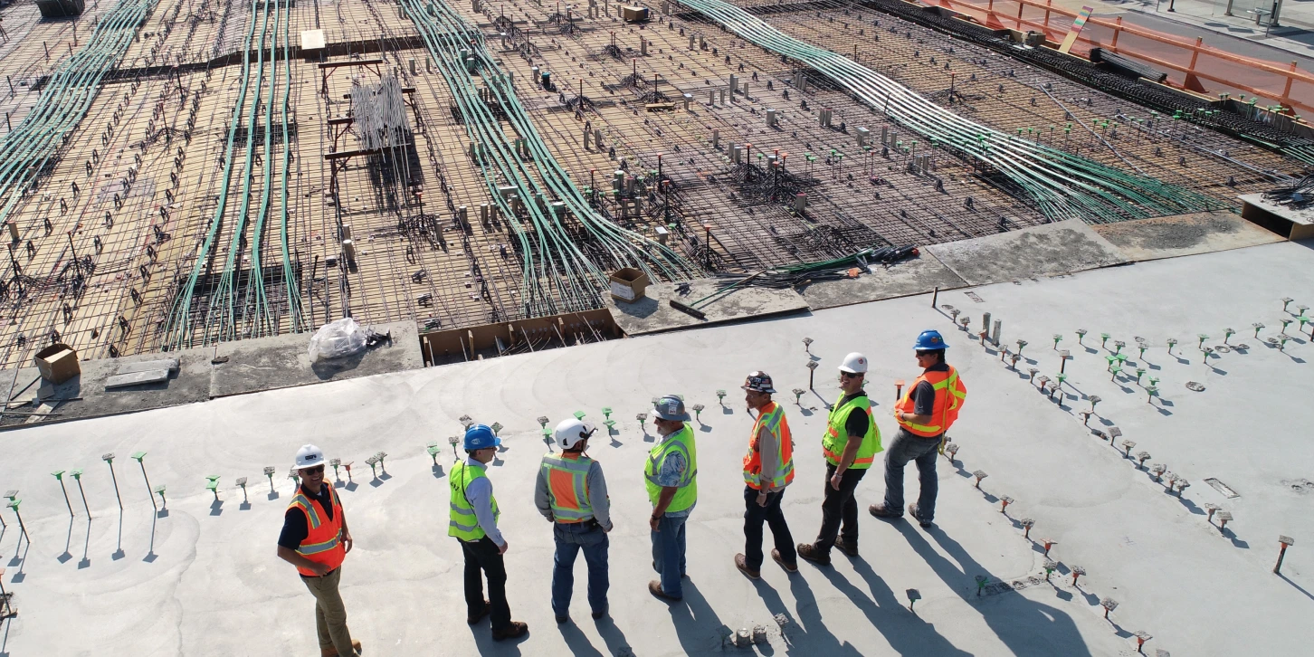 Construction workers working on a site overlooking the foundations of the structure.