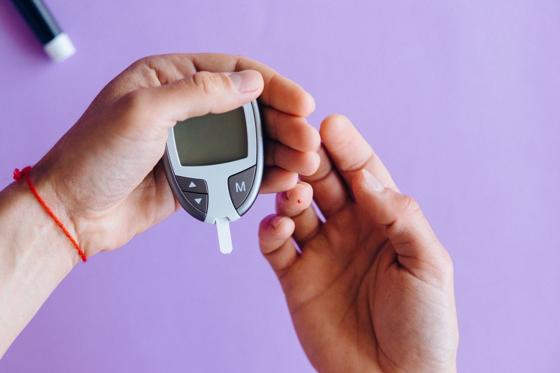 Person holding a glucose meter to check blood sugar levels