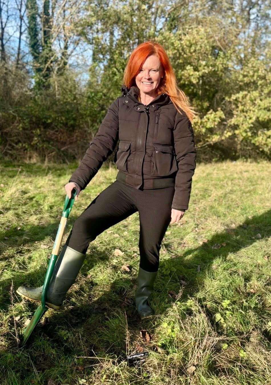 Smiling woman with red hair working outdoors with garden spade