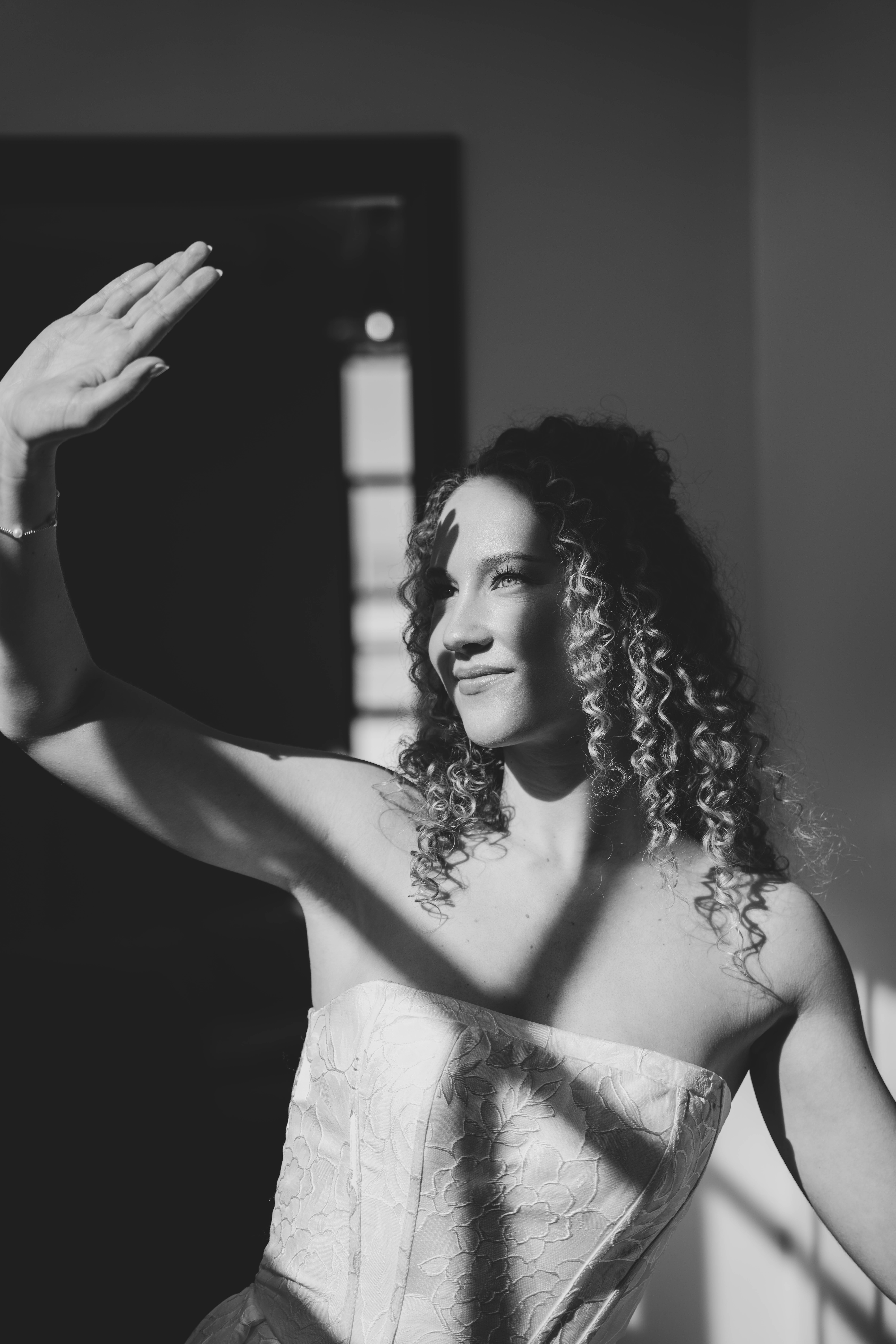 Black and white photo of a group raising champagne glasses in a celebratory toast at a dining table.