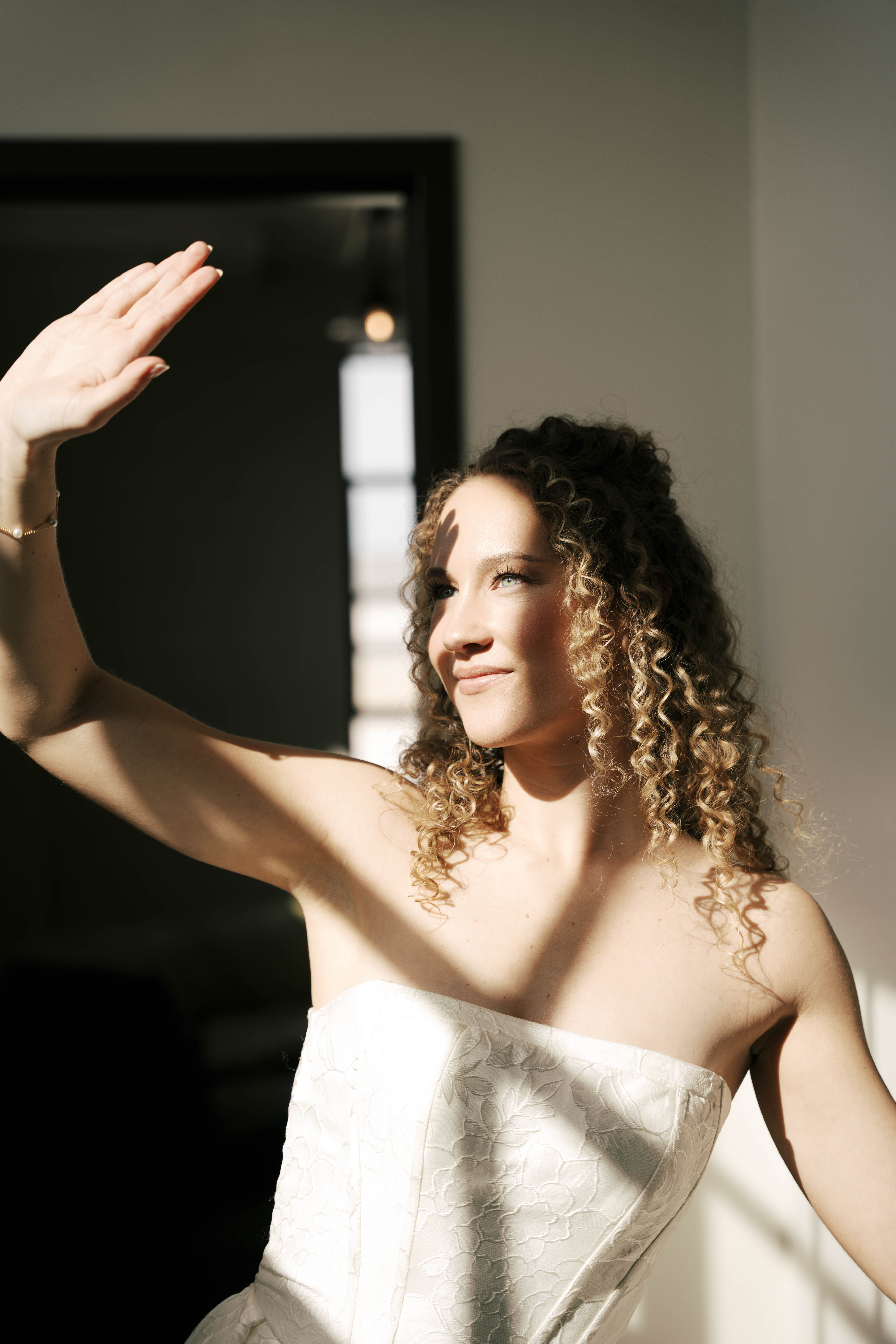 Couple sharing a kiss outdoors in front of stone archways, with the woman in a white dress and the man in a beige shirt.