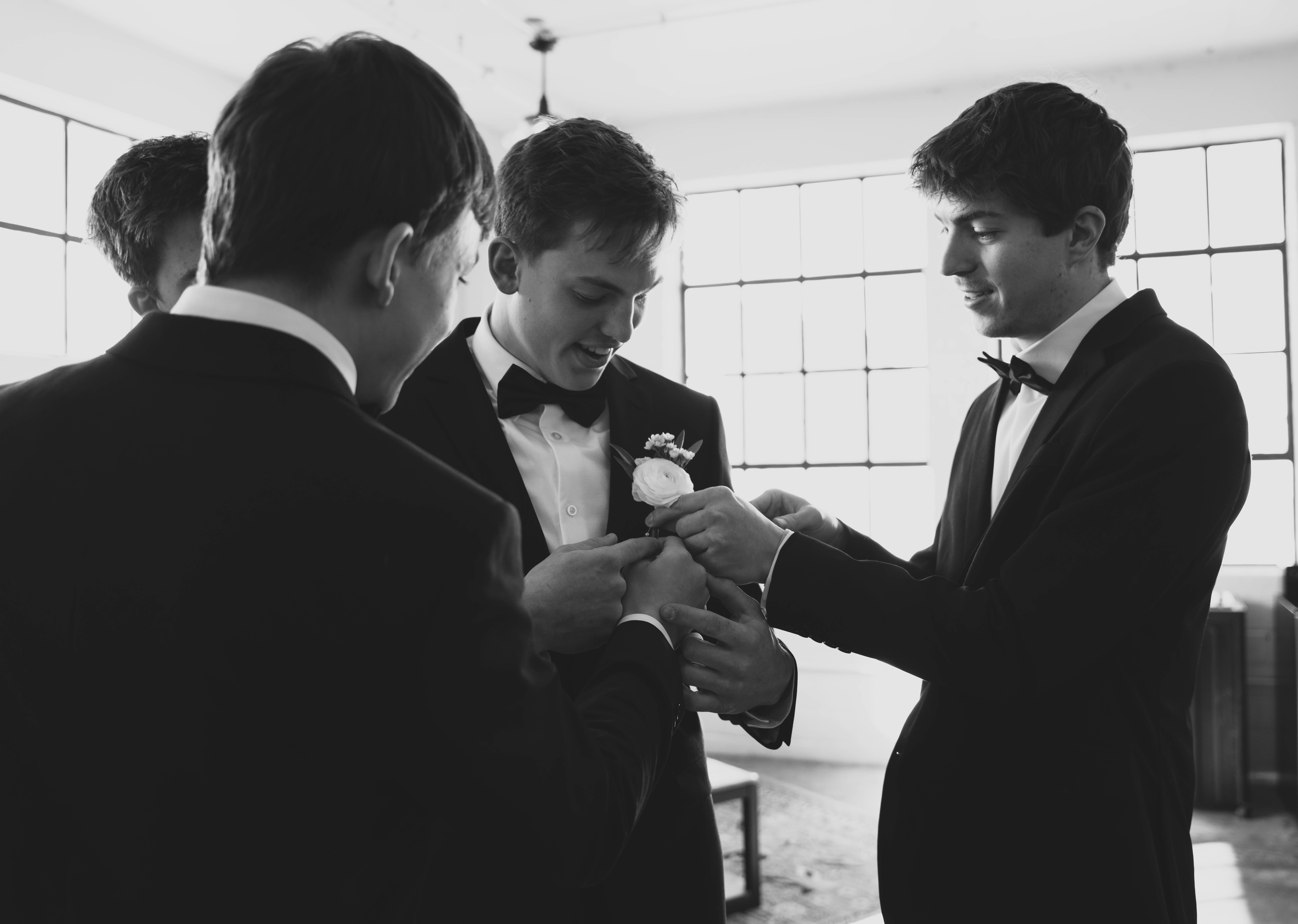 Man in red jacket hugging person wearing blue knitted hat outdoors, holding a bottle of champagne.