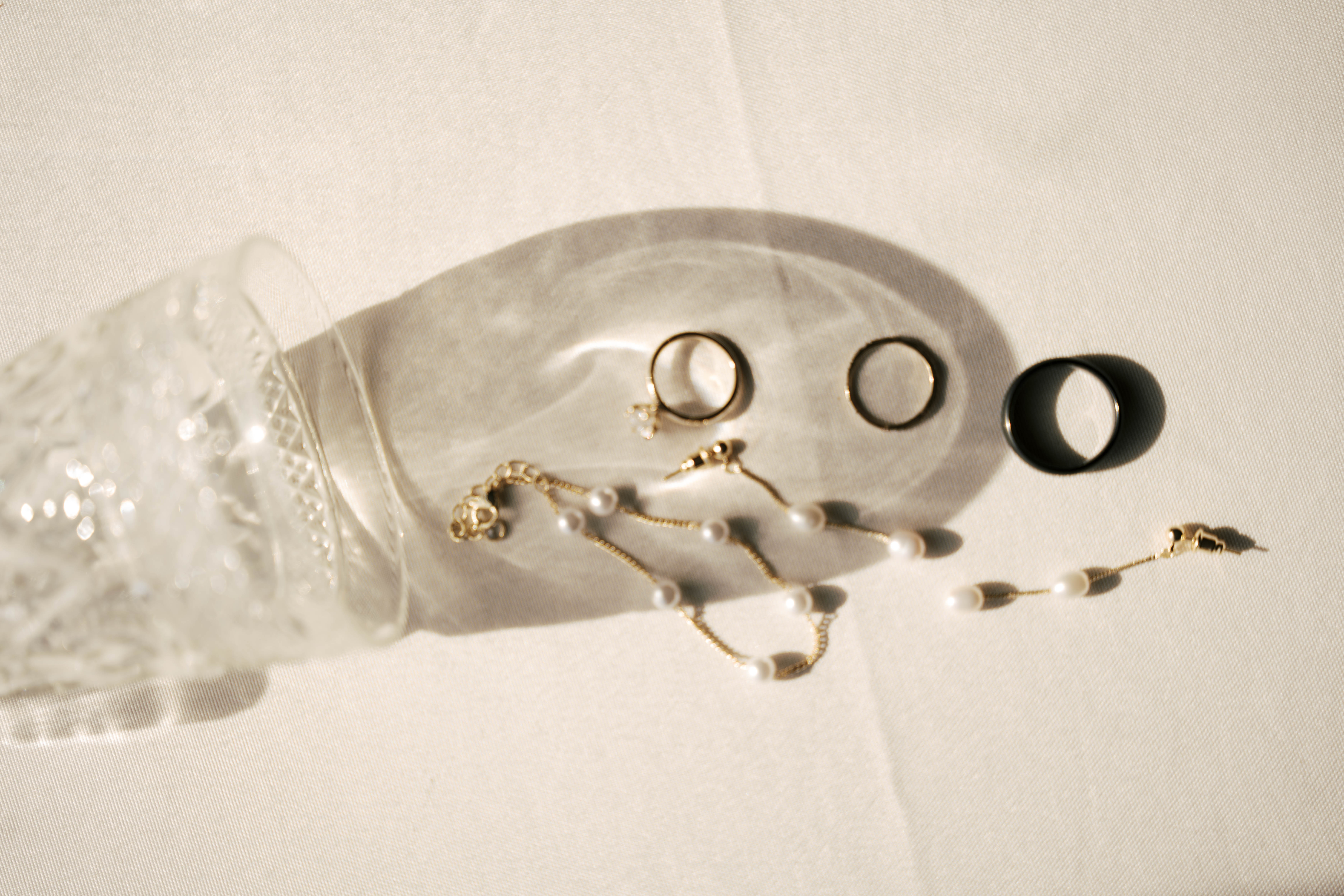 Two hikers with backpacks and arm around each other standing on a bridge overlooking a wooded valley with hills in the background.