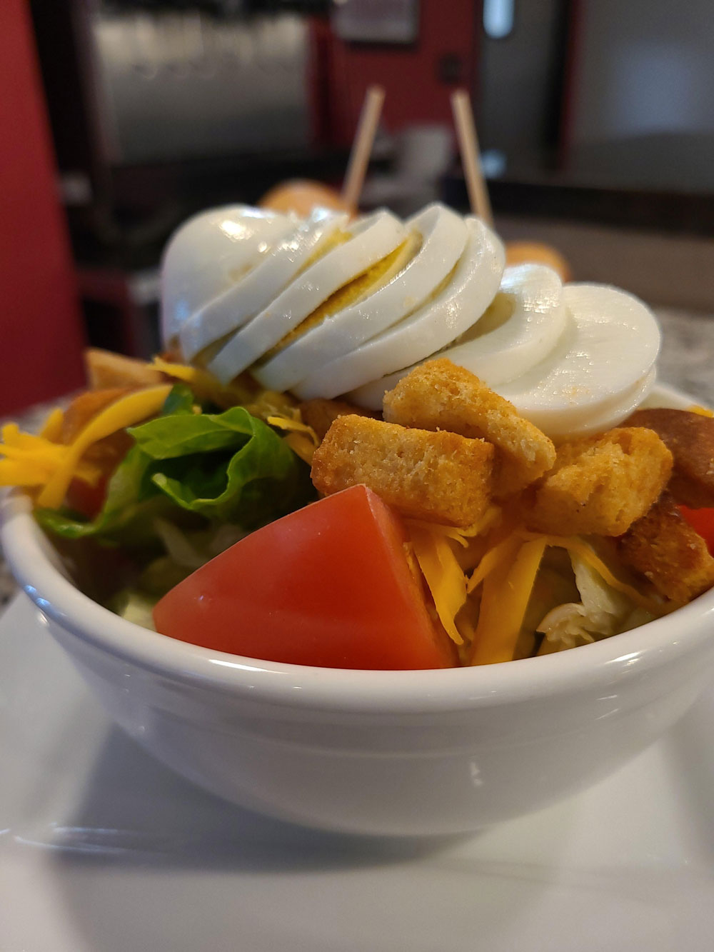A bowl of food with eggs, tomatoes, lettuce, and cheese.