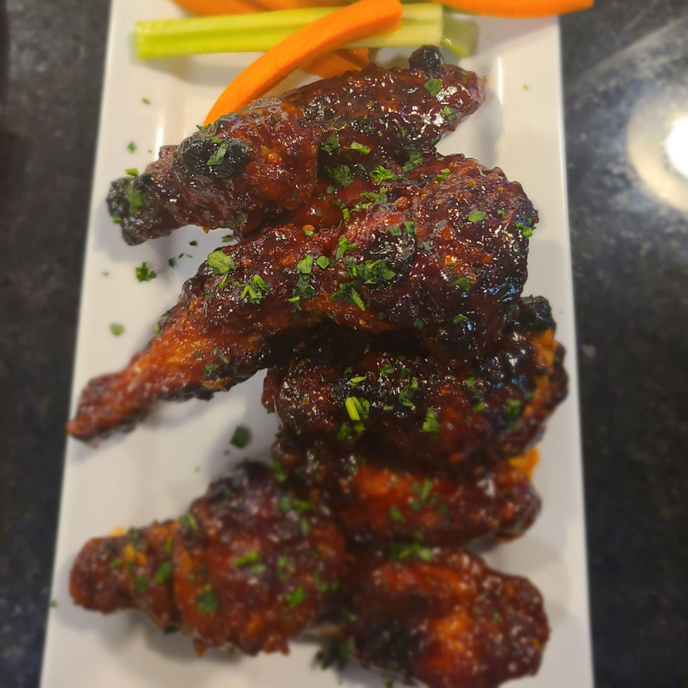 A plate of chicken wings with a side of carrots.