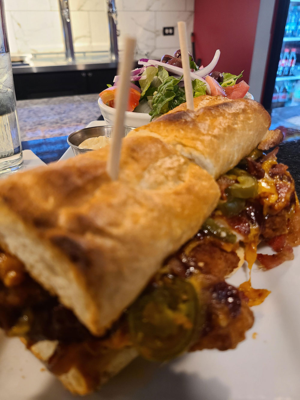 A sandwich with meat and vegetables on a white plate.