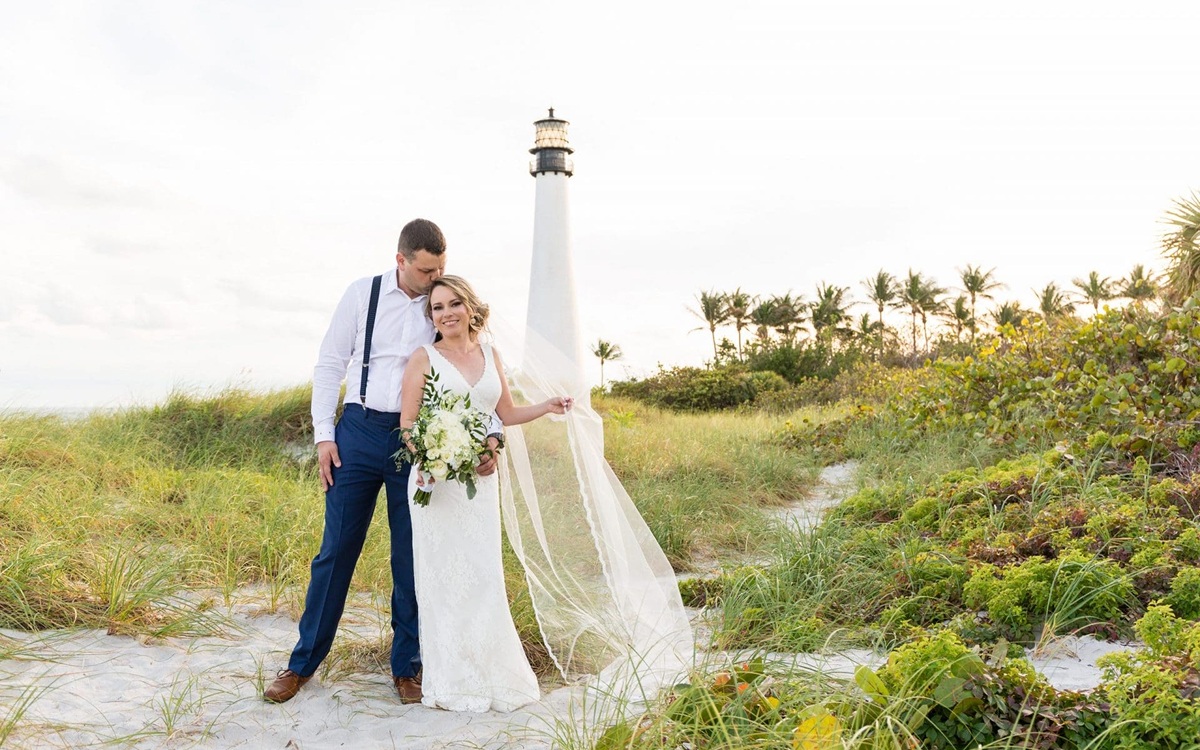 Bride and groom standing together on a historic stone staircase surrounded by trees and textured stone walls.