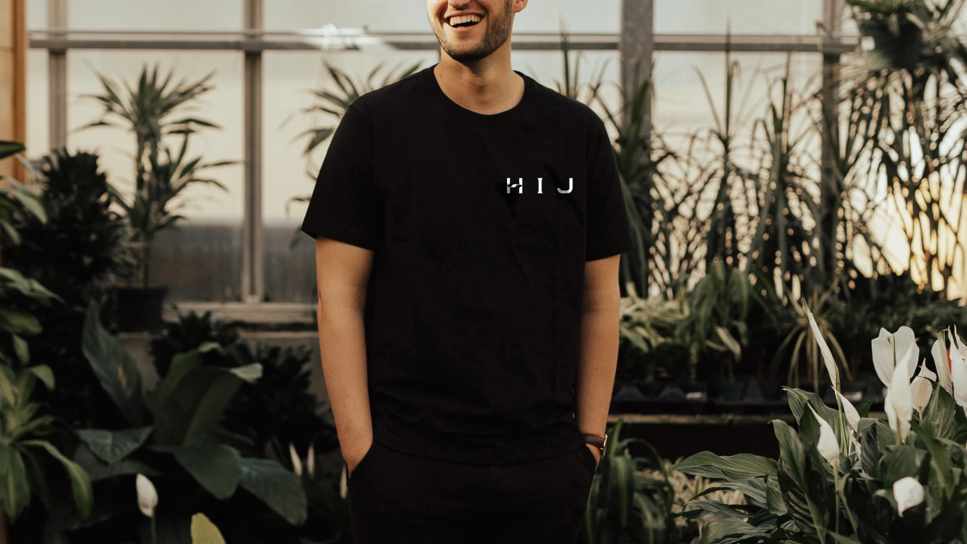 Man wearing an HIJ shirt surrounded by plants