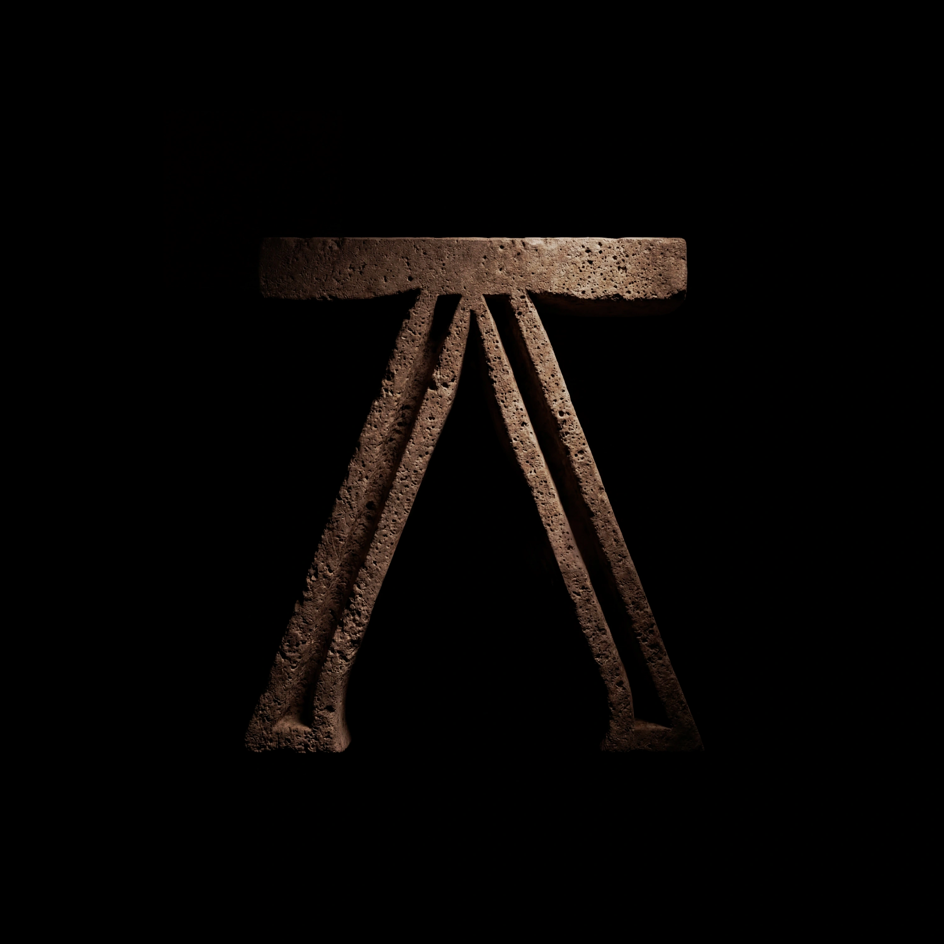 A carved stone symbol shaped like a stylized "A," spotlighted against a black background.