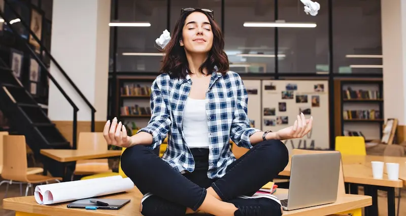 Jeune professionnelle méditant au bureau pour illustrer le bien-être et l’épanouissement au travail