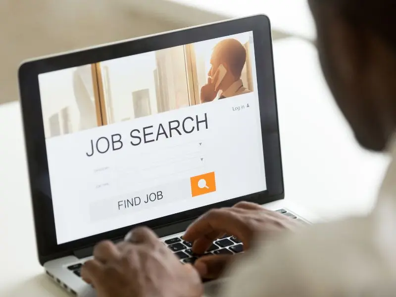Homme de 58 ans utilisant un ordinateur pour rechercher un emploi, consulter des offres et participer à une formation en ligne, ambiance professionnelle et positive.