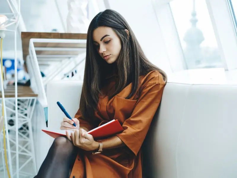 Personne prenant des notes pour identifier ses intérêts, ses compétences et ses priorités professionnelles.