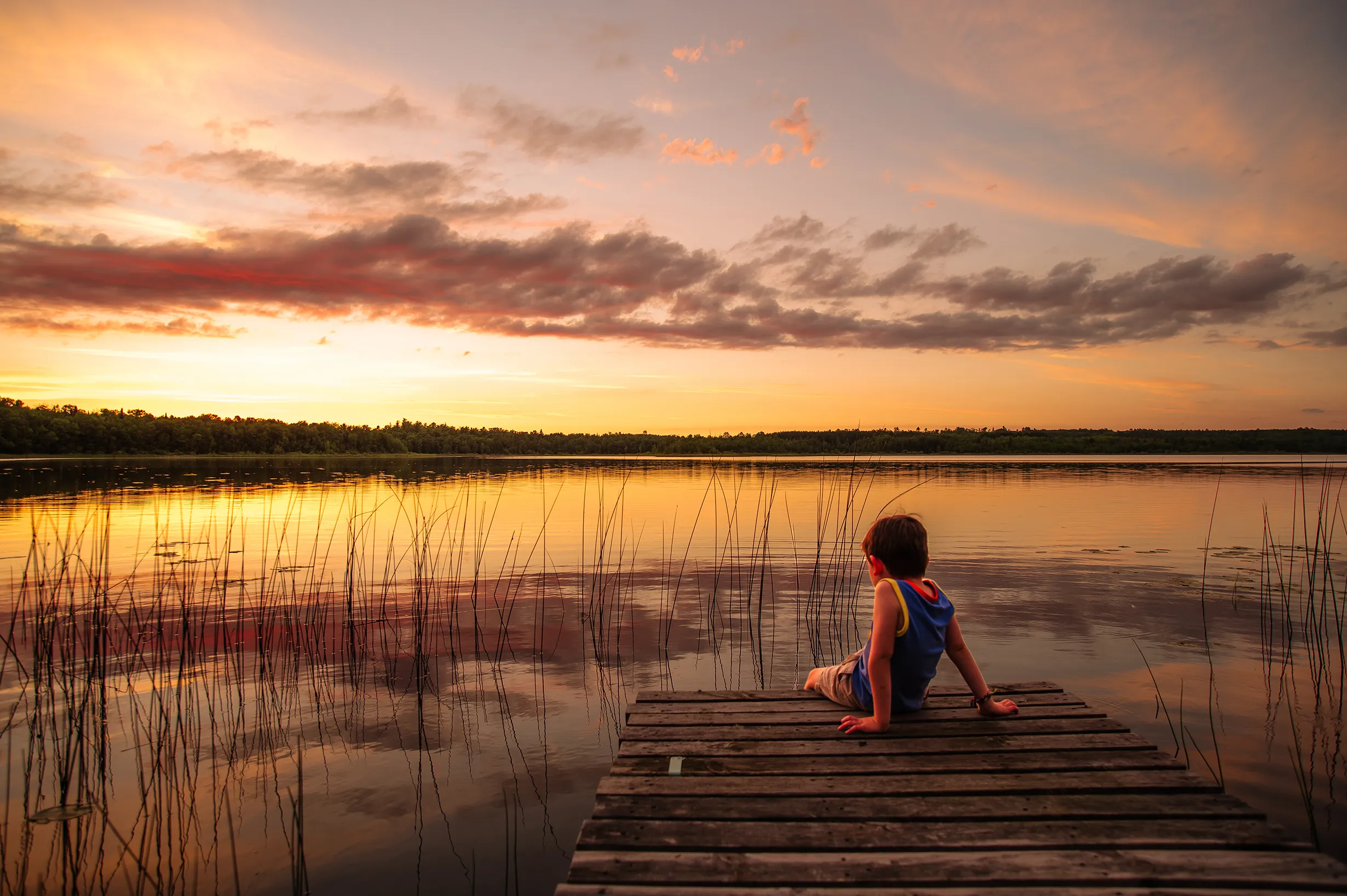 Minnesota Lake Sunset with a boy on the dock.