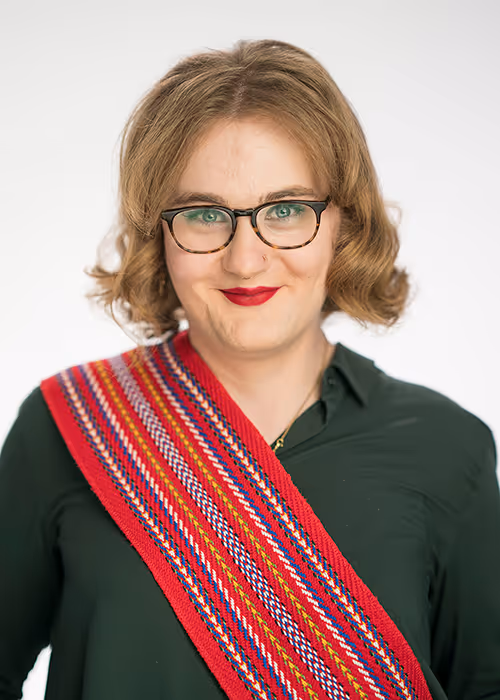 Portrait of Cayleigh Borboom, Saxophone, wearing glasses and a dark green top with a red patterned sash.