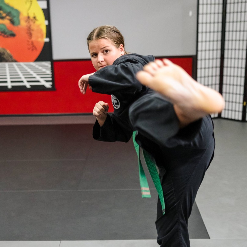 A USSD Oceanside karate student showing off her side thrust kick as her foot flies close to the camera