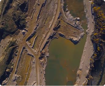 Aerial view of an excavator operating at a muddy riverbank construction site.