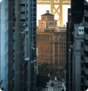 View of an ornate historic building framed by modern skyscrapers in a cityscape during daylight.
