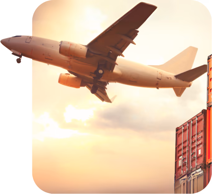 Cargo airplane flying over stacked shipping containers at sunset.