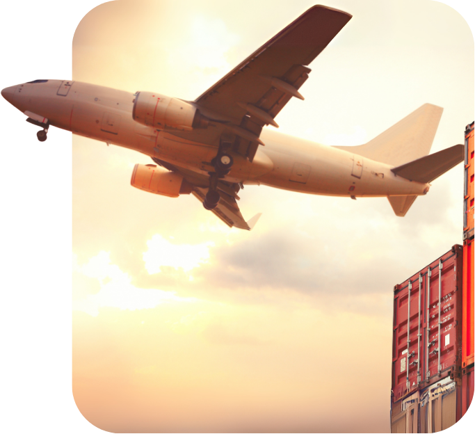 Cargo airplane flying over stacked shipping containers at sunset.