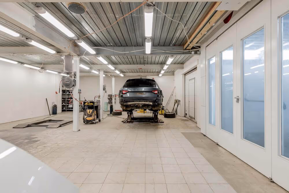Car lifted on a hydraulic lift inside a spacious, well-lit auto repair garage.