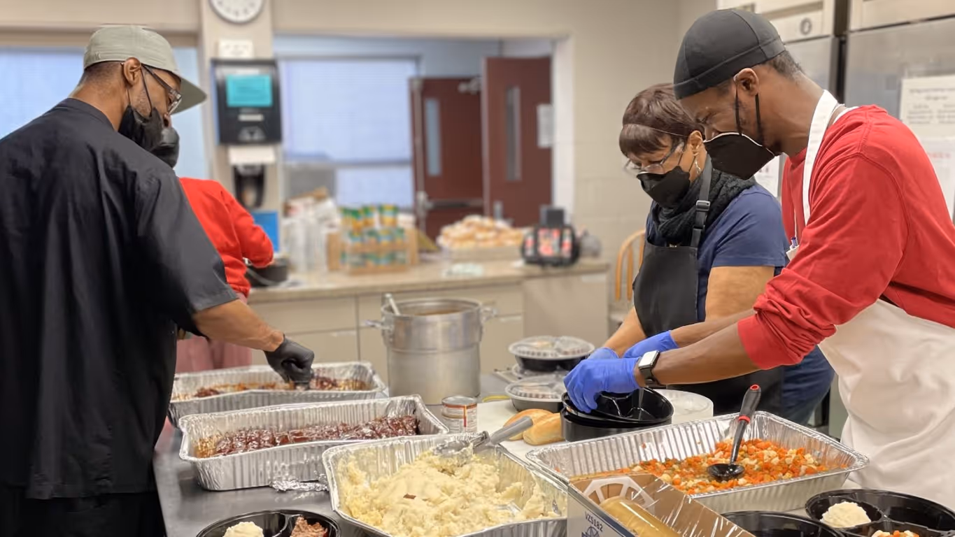 Master's Kitchen staff wear masks as they prepare a meal of ribs, mashed potatoes, and mixed vegetables