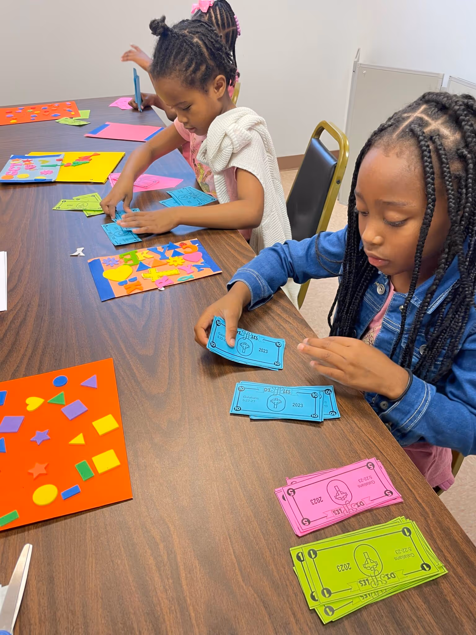 Students sit at a table counting their colorful DiSYPles Dollars