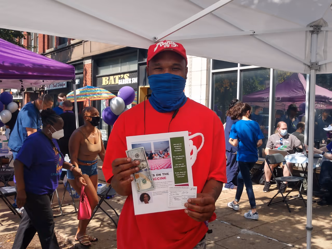 A participant at a vaccine clinic event in East Liberty poses for the camera with his vaccine card and cash incentive.