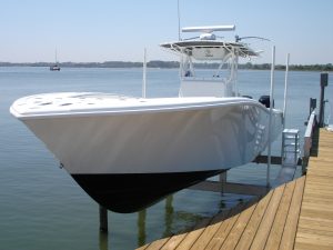 A boat elevator contains a white v-hull vessel and is mounted on one side to a dock.