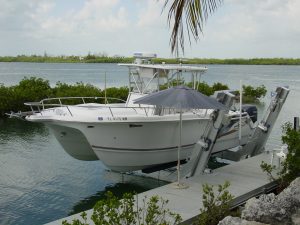 A boat elevator lift attached to the seawall in Florida holds a medium-sized vessel.