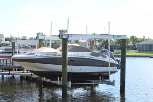 A 10,000 lb. cradle boat lift holding a v-hull vessel off a dock in Florida.