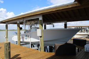 A white boat in a boathouse lift built off a dock.