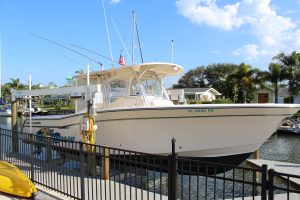 A large v-hull boat suspended on a boat lift behind a black aluminum fence.