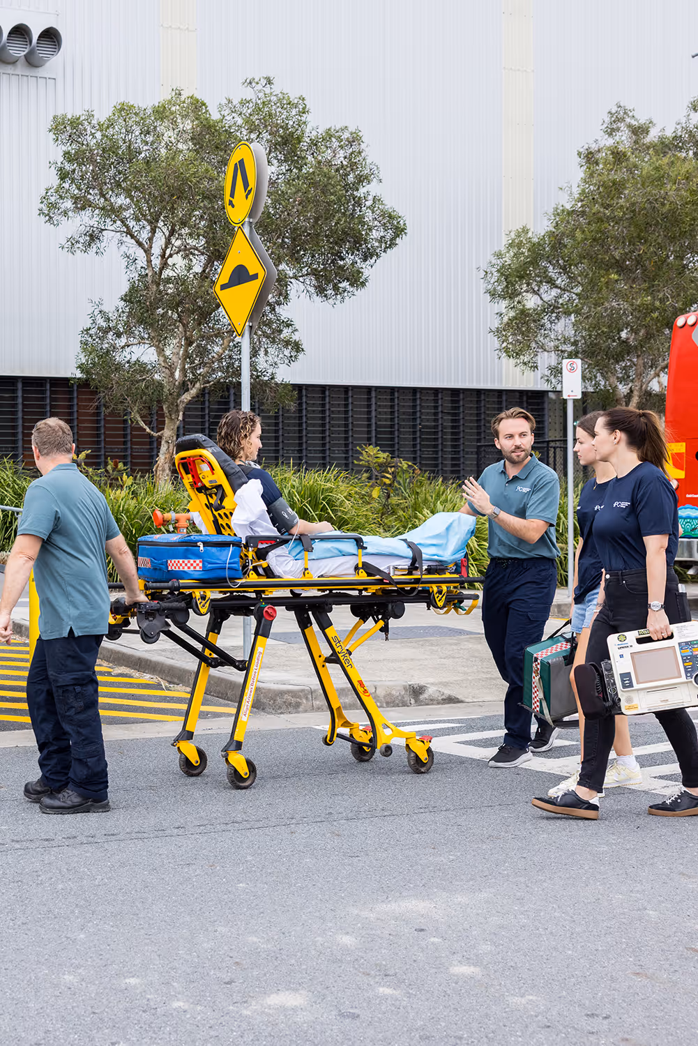 Paramedics transporting a patient on a stretcher across a street, with medical equipment carried by team members.