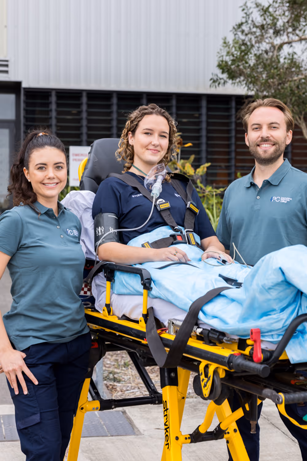 Two paramedics standing beside a patient lying on a stretcher outside a medical facility.