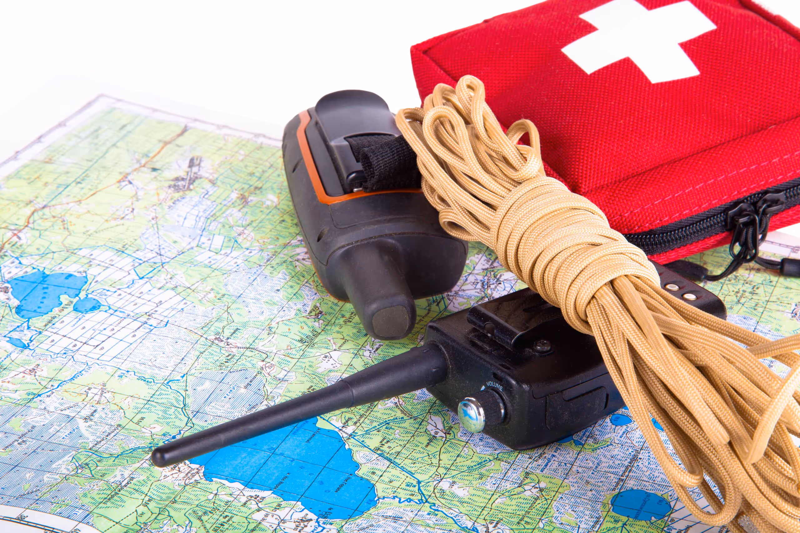 Emergency preparedness equipment, including a radio, rope, and first aid kit placed on a map