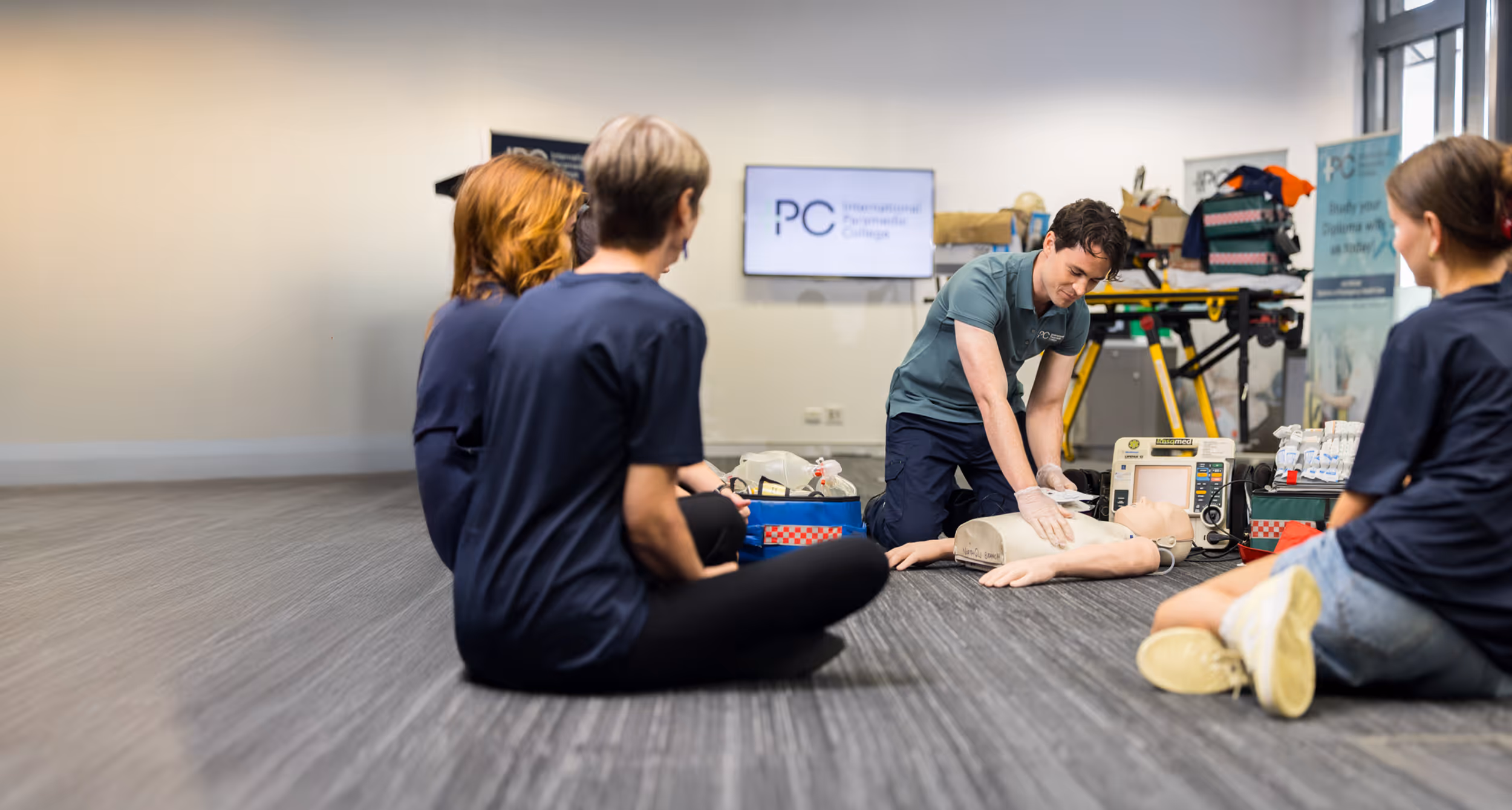 An instructor demonstrates CPR and resuscitation techniques on a training mannequin while a small group of students observe during an advanced resuscitation and oxygen therapy course.