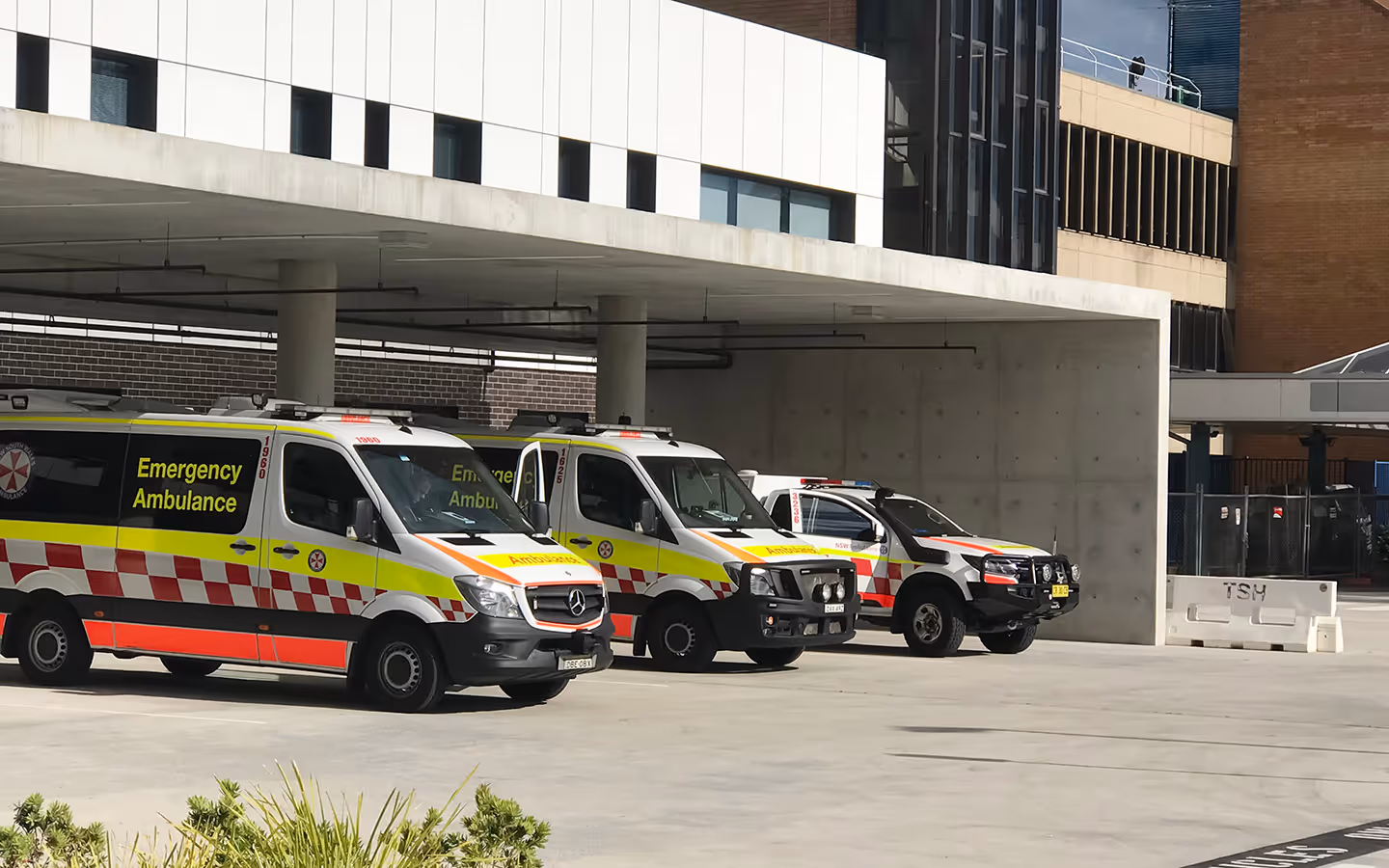 Emergency ambulances parked outside a hospital entrance.