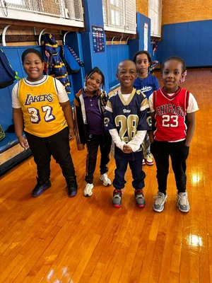 Five children standing on a polished gym floor 