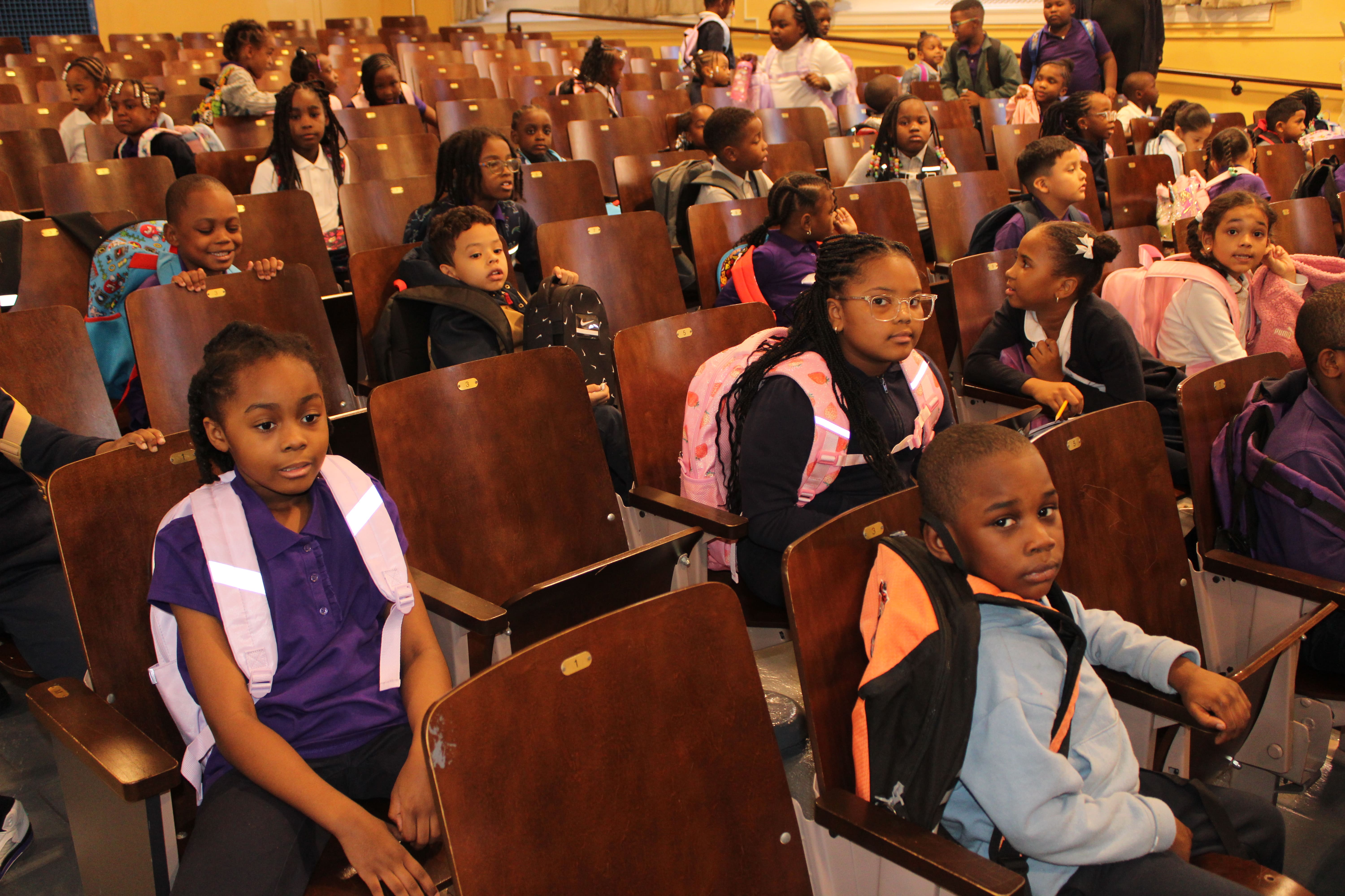 Five children standing on a polished gym floor 
