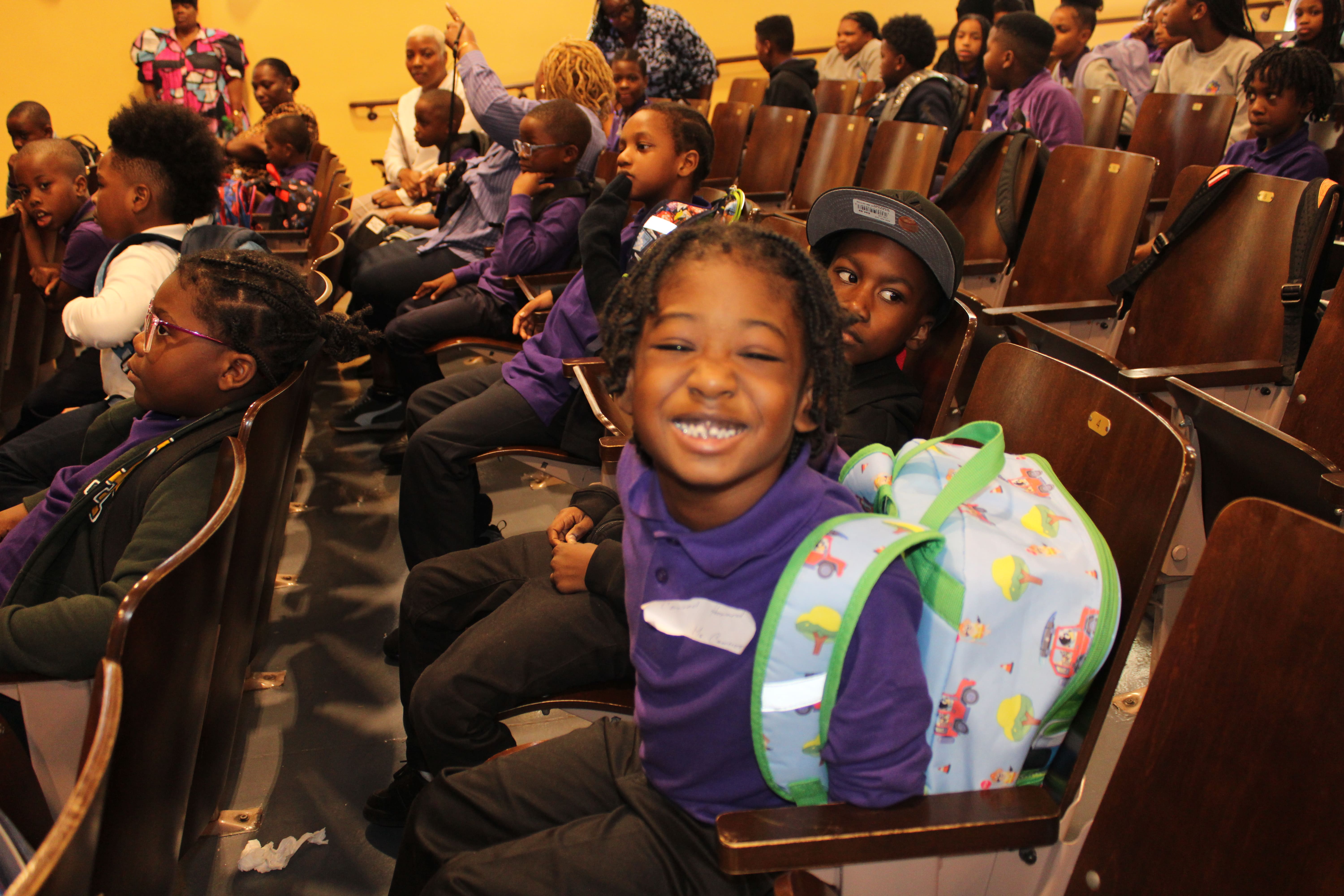 Five children standing on a polished gym floor 